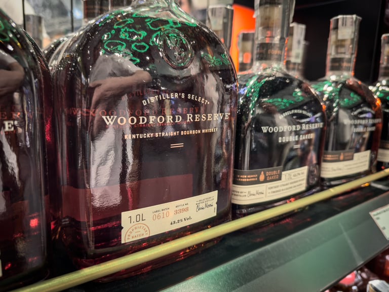 Close-up view of bottles of Woodford Reserve Kentucky Straight Bourbon Whiskey displayed on a shelf with rich amber color visible